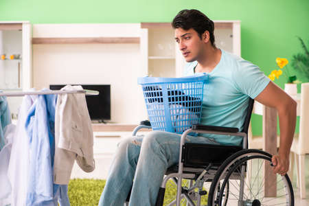 Disabled man on wheelchair doing laundryの写真素材
