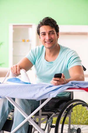 Disabled man on wheelchair ironing clothingの写真素材