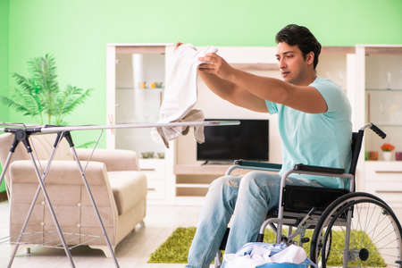 Disabled man on wheelchair doing laundryの写真素材