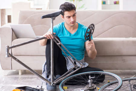 Young man repairing bicycle at homeの写真素材