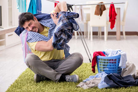Handsome man husband doing laundering at homeの写真素材