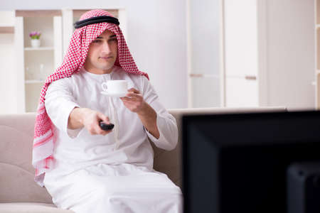 Arab man watching tv at homeの写真素材