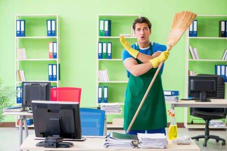 Young male handsome professional cleaner cleaning floor with bro