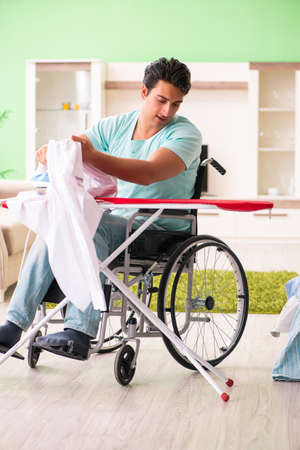 Disabled man on wheelchair ironing clothingの写真素材