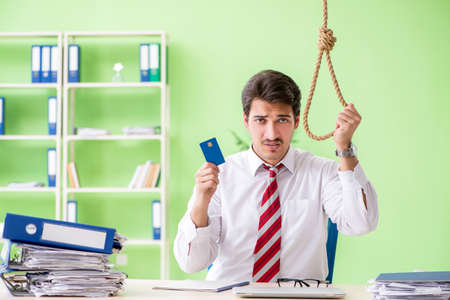 Despaired businessman thinking of suicide in the officeの写真素材