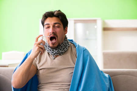 Sick young man suffering from flu at homeの写真素材