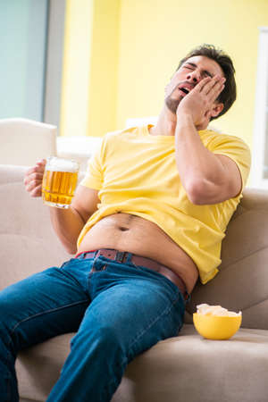 Fat obese man holding beer in dieting conceptの写真素材