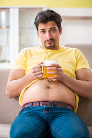 Fat obese man holding beer in dieting conceptの写真素材