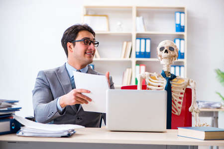 Businessman working with skeleton in officeの写真素材