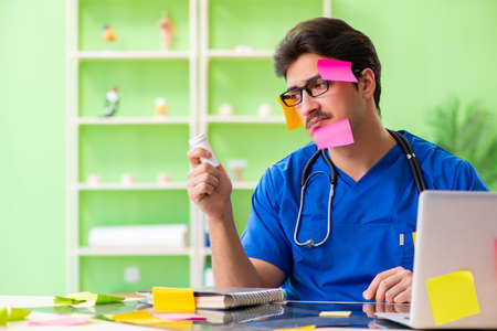 Young doctor sitting in hospital with many conflicting prioritie