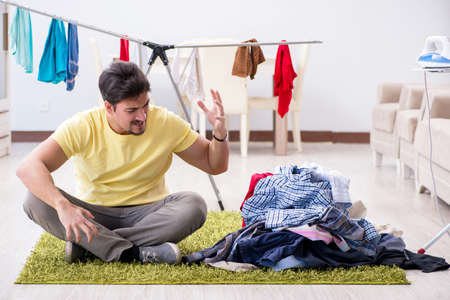 Handsome man husband doing laundering at homeの写真素材