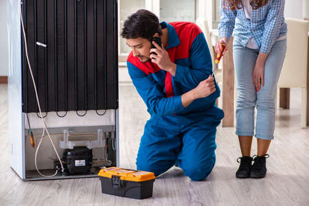 Man repairing fridge with customerの写真素材