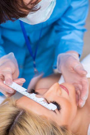 Female ophthalmologist is checking up female patient in eye doctの写真素材