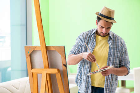 Young male artist working on new painting in his studioの写真素材