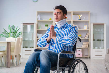 Young man suffering from injury on wheelchair at homeの写真素材