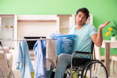 Disabled man on wheelchair doing laundryの写真素材