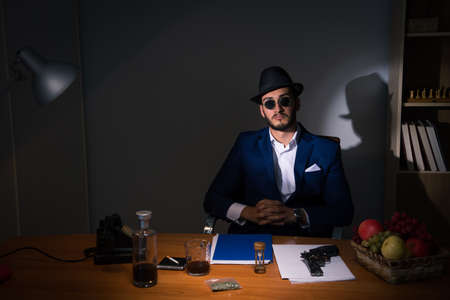 Detective sitting in dark room in vintage conceptの写真素材