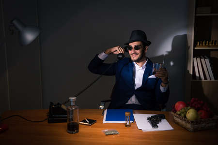 Detective sitting in dark room in vintage conceptの写真素材