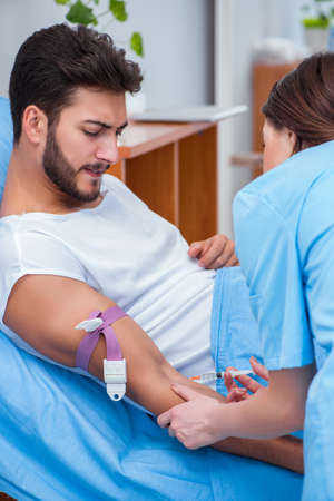 Woman doctor examining male patient in hospitalの写真素材