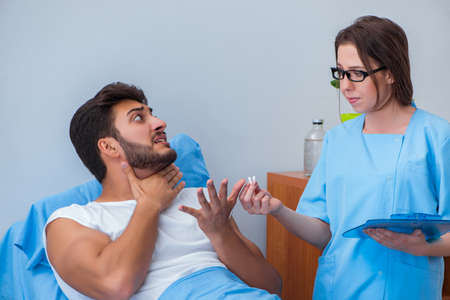 Woman doctor examining male patient in hospitalの写真素材
