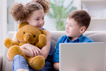 Two kids sitting at laptop at homeの写真素材