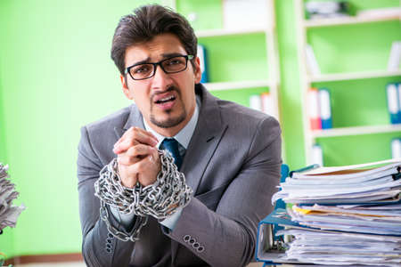 Employee chained to his desk due to workloadの写真素材