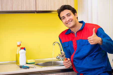 Plumber repairing tap at kitchenの写真素材