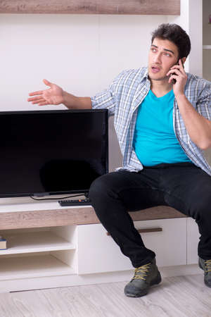 Man trying to fix broken tvの写真素材