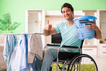 Disabled man on wheelchair doing laundryの写真素材