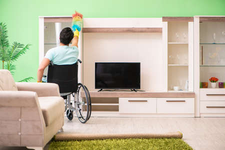 Disabled man on wheelchair cleaning houseの写真素材