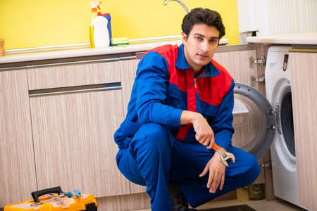 Repairman repairing washing machine in the kitchenの写真素材