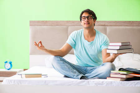Student preparing for exams at home in bedroom sitting on the beの写真素材