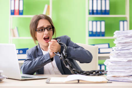 Young female employee  busy with ongoing paperwork chained to thの写真素材