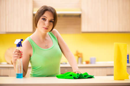 Young beatifull woman polishing table in the kitchen