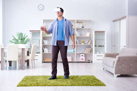 Man with virtual reality glasses playing at homeの写真素材