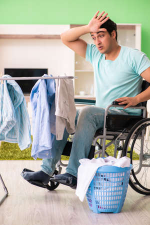 Disabled man on wheelchair doing laundryの写真素材