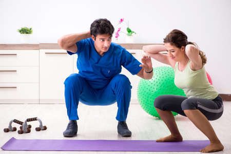 Fitness instructor helping sportsman during exerciseの写真素材