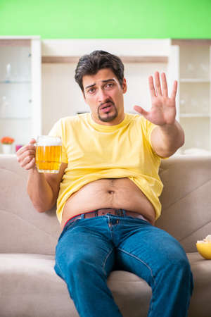 Fat obese man holding beer in dieting conceptの写真素材