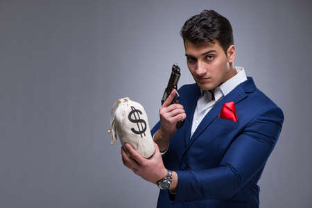 A handsome man holding a gun against gray backgroundの写真素材
