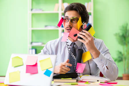 Young help desk operator working in office with many conflicting prioritiesの写真素材