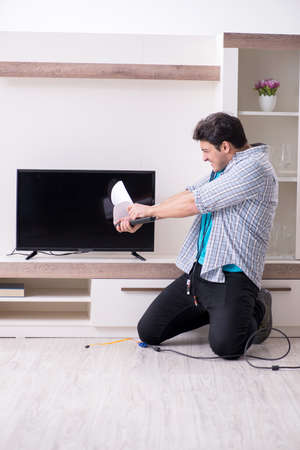 A man trying to fix a broken televisionの写真素材