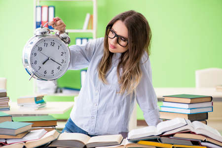 Young female student preparing for exams with many books in timeの写真素材