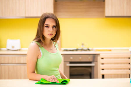 Young beatifull woman polishing table in the kitchen