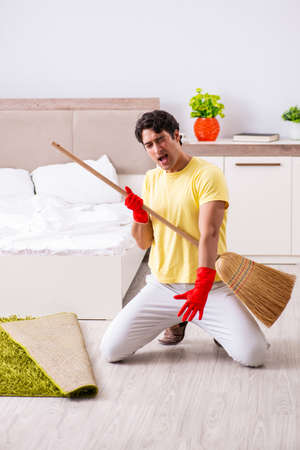 Young handsome man cleaning in the bedroomの写真素材
