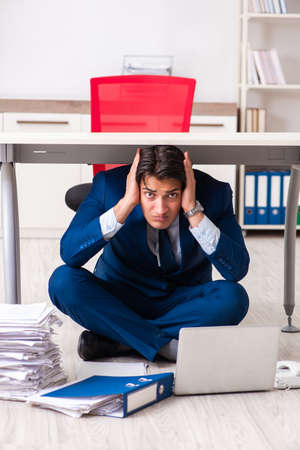 Tired exhausted businessman working overtime in officeの写真素材