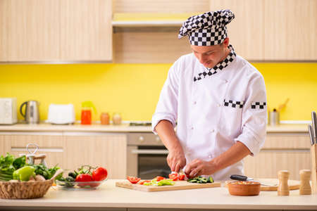 Young professional cook preparing salad at kitchen