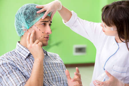 Plastic surgeon preparing for operation on man faceの写真素材