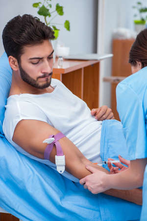 Woman doctor examining male patient in hospitalの写真素材