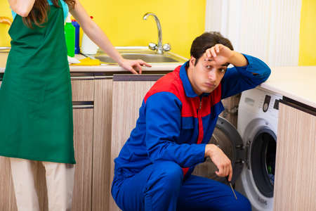 Contractor repairing washing machine at homeの写真素材
