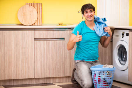 Young husband man doing laundry at homeの写真素材
